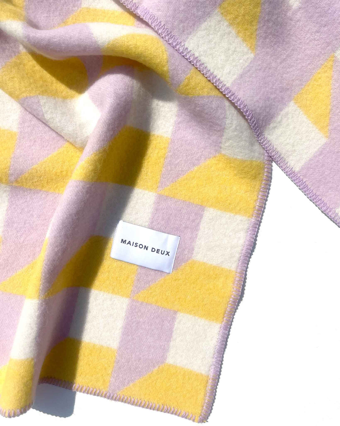 Wolldecke von Maison Deux in den Farben Lila, Gelb und Weiss mit lila vernähtem Rand