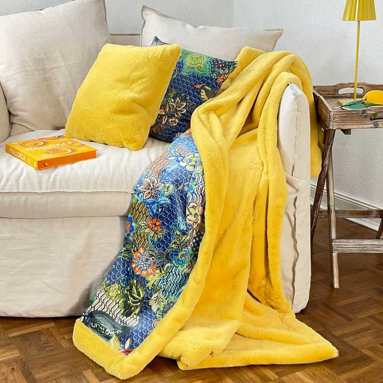 Carma Tender Webpelz-Decke in Lemon Gelb und Samt Lotus Blau – weiche, luxuriöse Textur mit lebendigen Farbtönen, dekorativ drapiert.