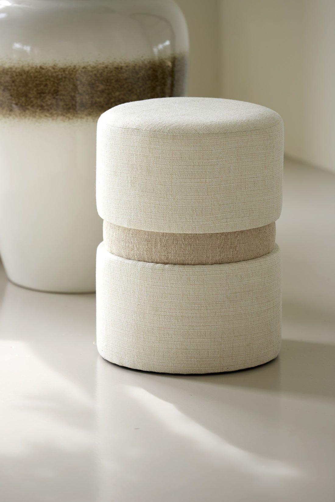 Moderner Pouf mit weichem Textilbezug in neutralen Farbtönen