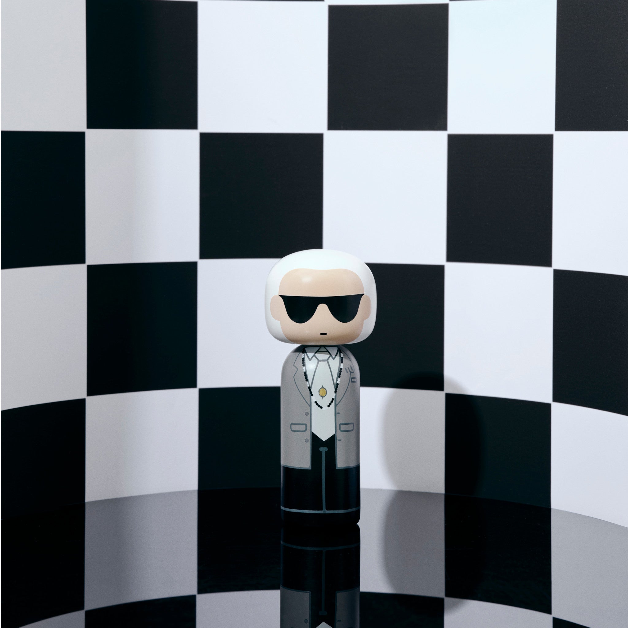 Handbemalte Kokeshi auf Podest vor rosa Hintergrund inspiriert von Karl Lagerfeld