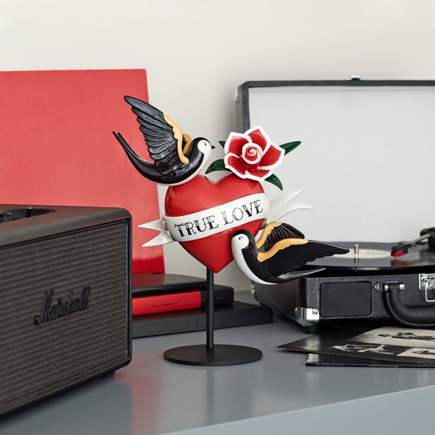 Liebevoll gestaltete Figur mit roten Rosen, Schwalben und dem Schriftzug "True Love".