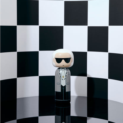 Handbemalte Kokeshi auf Podest vor rosa Hintergrund inspiriert von Karl Lagerfeld
