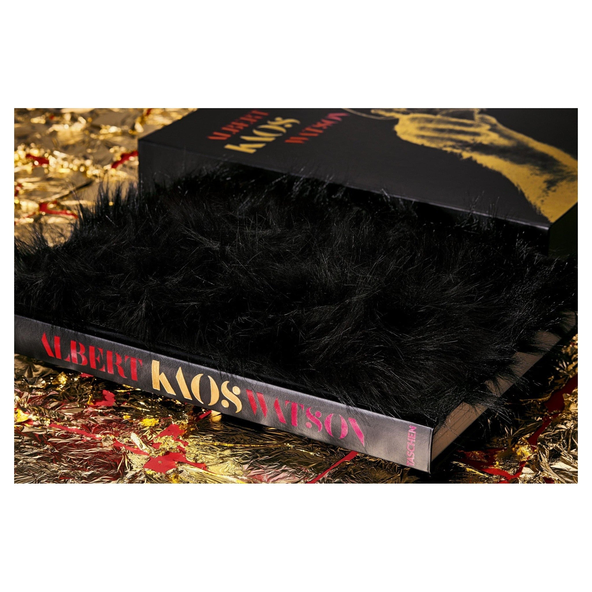 Goldfoliertes Hintergrunddesign mit markanten Strukturen neben dem KAOS Buch.